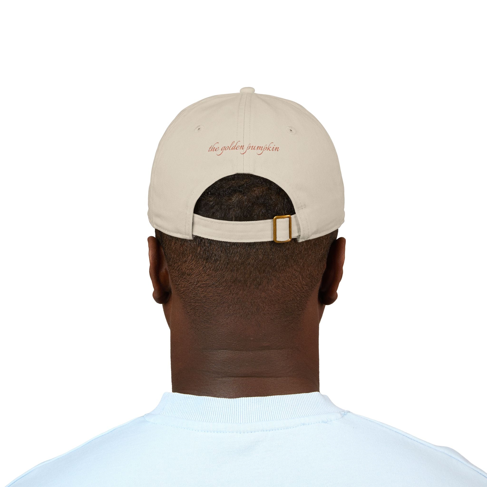 Male wearing a beige baseball cap with text 'the golden pumpkin' on the back, in rusty orange color. The golden pumpkin is the store name.