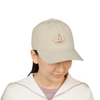 Women wearing beige baseball cap with embroidered jack-o-lantern pumpkin outline design on the front in a rusty orange color.
